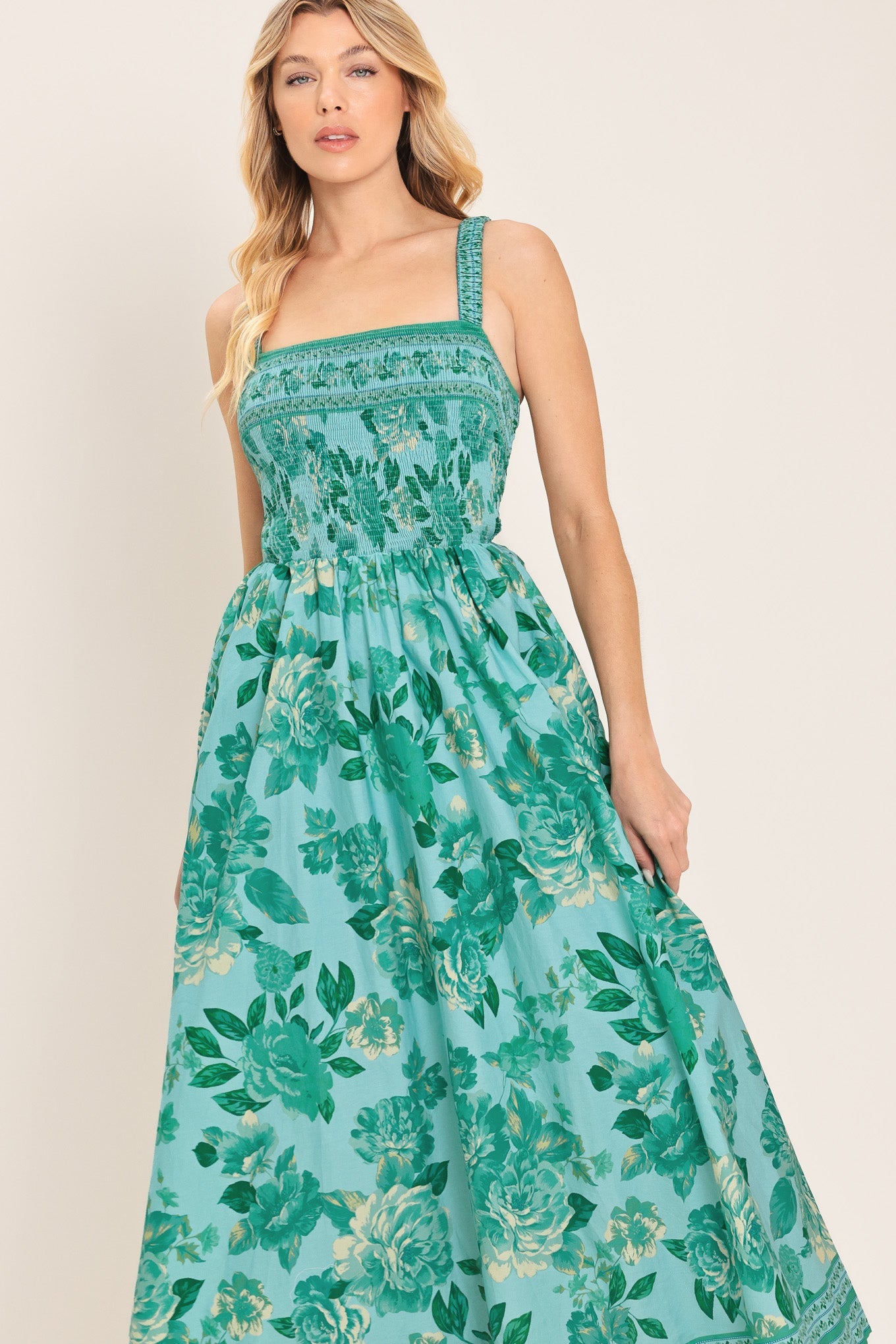 Woman wearing a green floral dress against a plain background