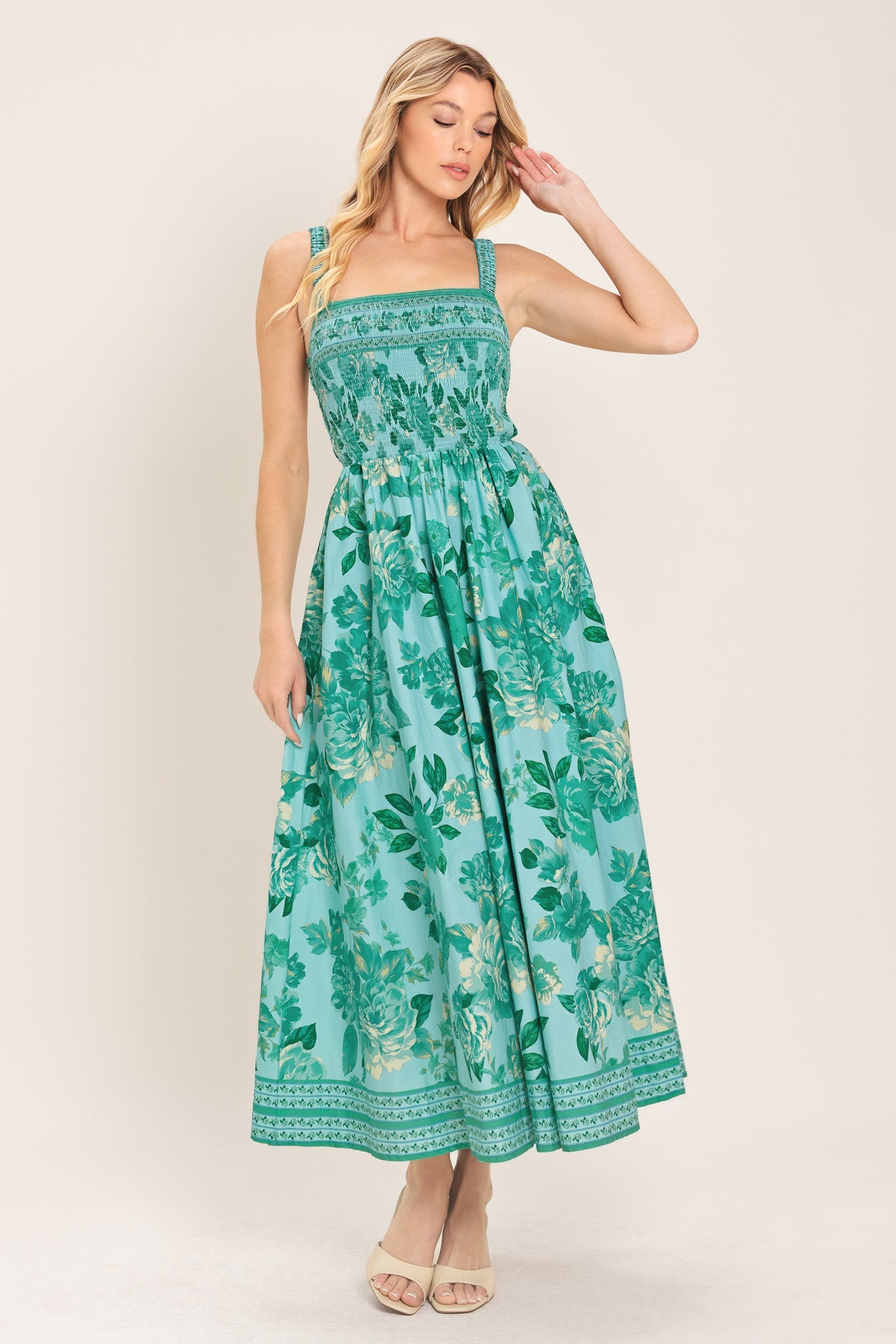 Woman wearing a green floral dress against a white background