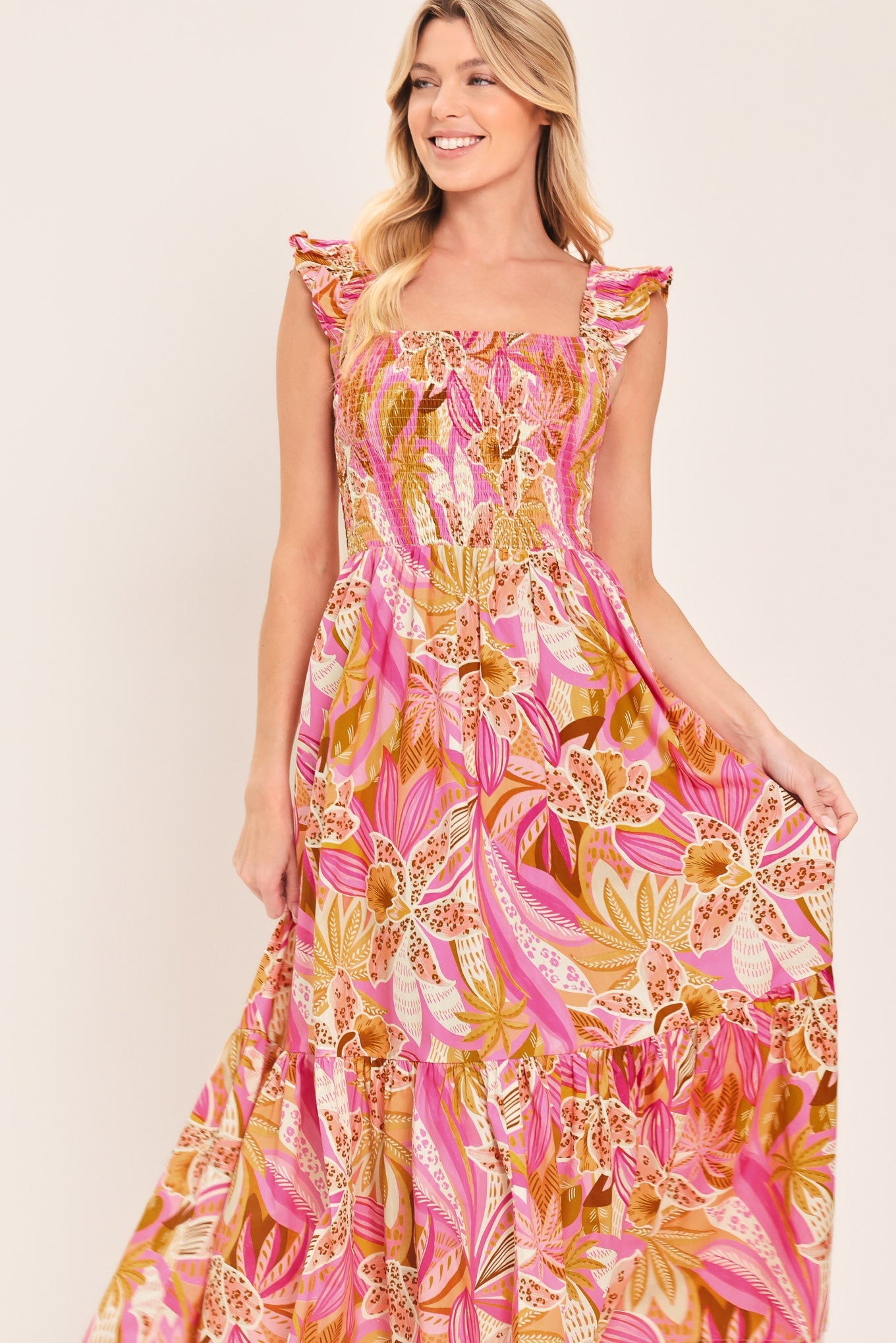 Woman wearing a floral dress with pink and yellow colors on a plain background
