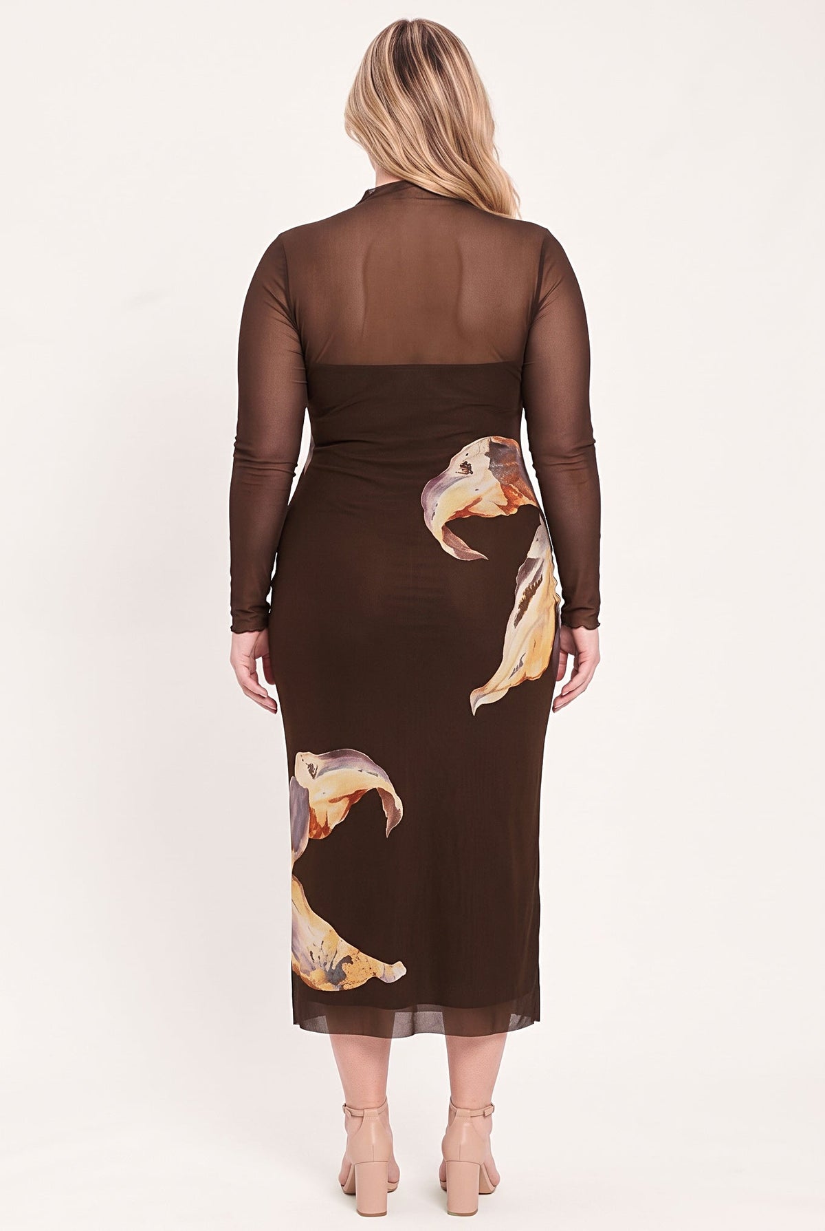 A woman viewed from the back wearing a sheer long-sleeve midi dress in dark brown with a printed pattern of large beige and orange ducks. She is standing against a plain off-white studio background.