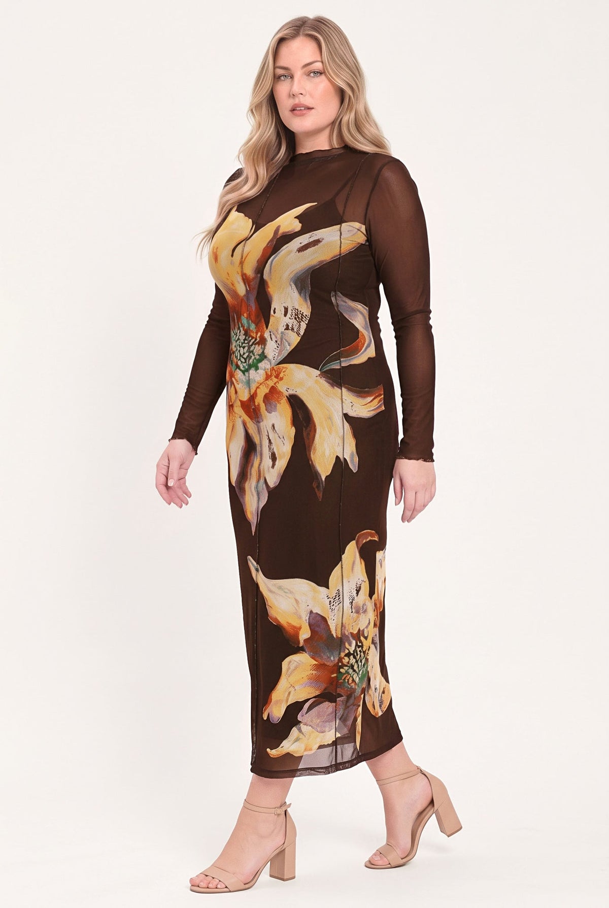 A woman modeling a sheer long-sleeve midi dress in dark brown with a large yellow and orange floral print, paired with beige high-heeled sandals, against a plain light background.