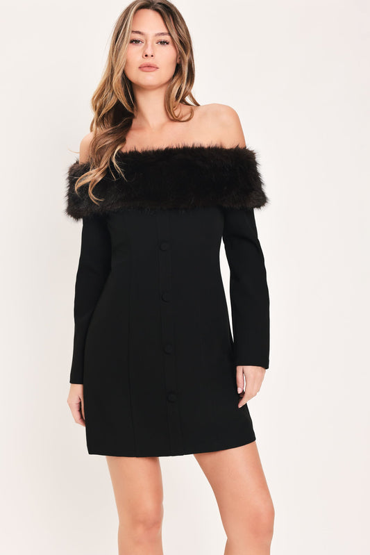 A woman modeling a black off-the-shoulder long-sleeve mini dress with a wide black faux-fur collar and a front button closure, photographed against a plain light background.