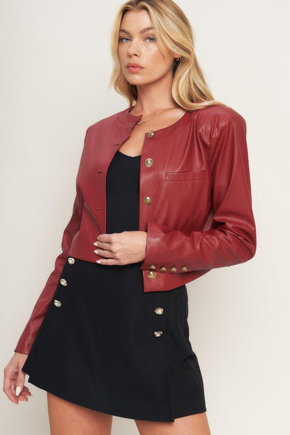 Woman wearing a red leather jacket over a black outfit on a plain background