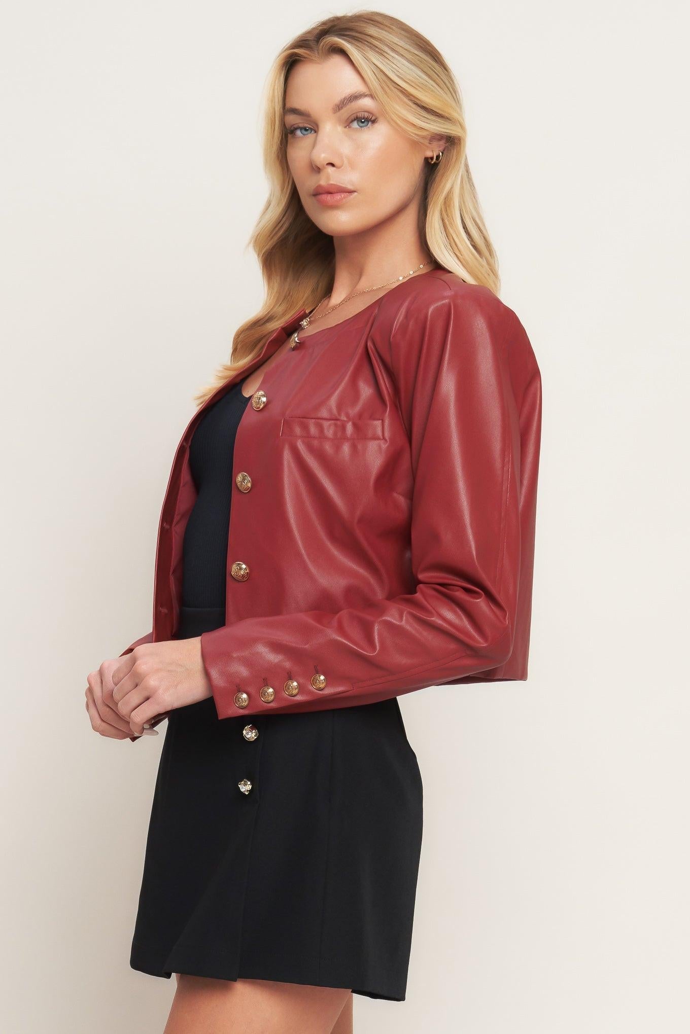 Woman wearing a red leather jacket over a black dress on a plain background