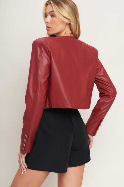 Woman wearing a red leather jacket and black shorts on a plain background