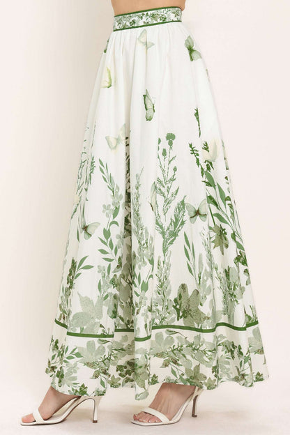 Long white skirt with green floral pattern worn by a model on a plain background