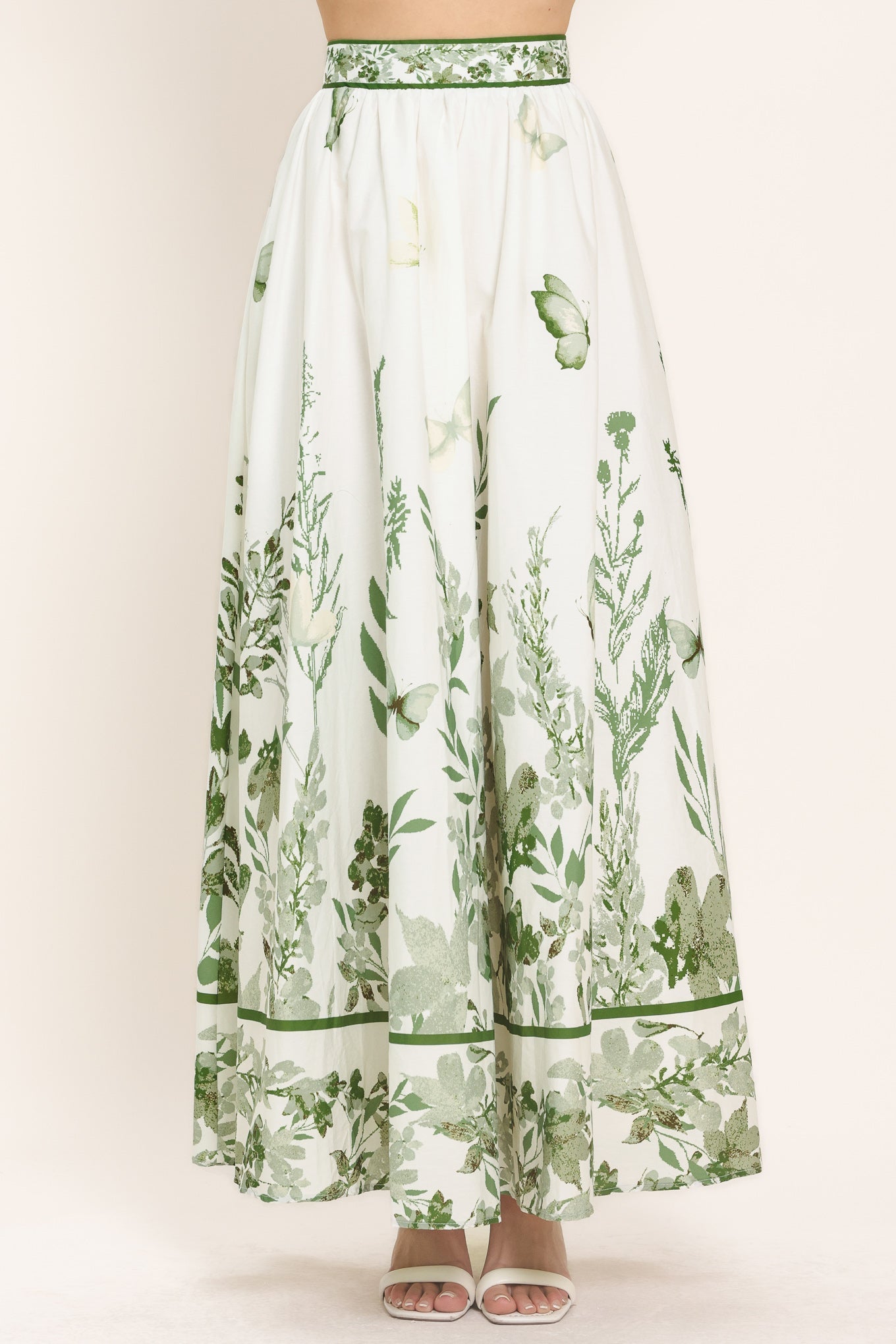Long white skirt with green floral pattern on a plain background