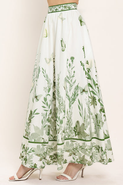 Long white skirt with green floral pattern worn by a model on a plain background