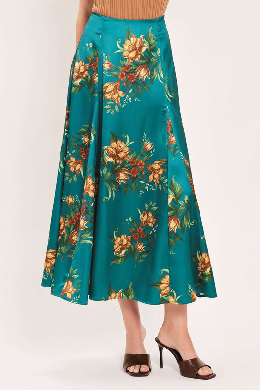 A teal green midi skirt with a vibrant orange and yellow floral print, worn by a model with brown heeled sandals against a plain light background.