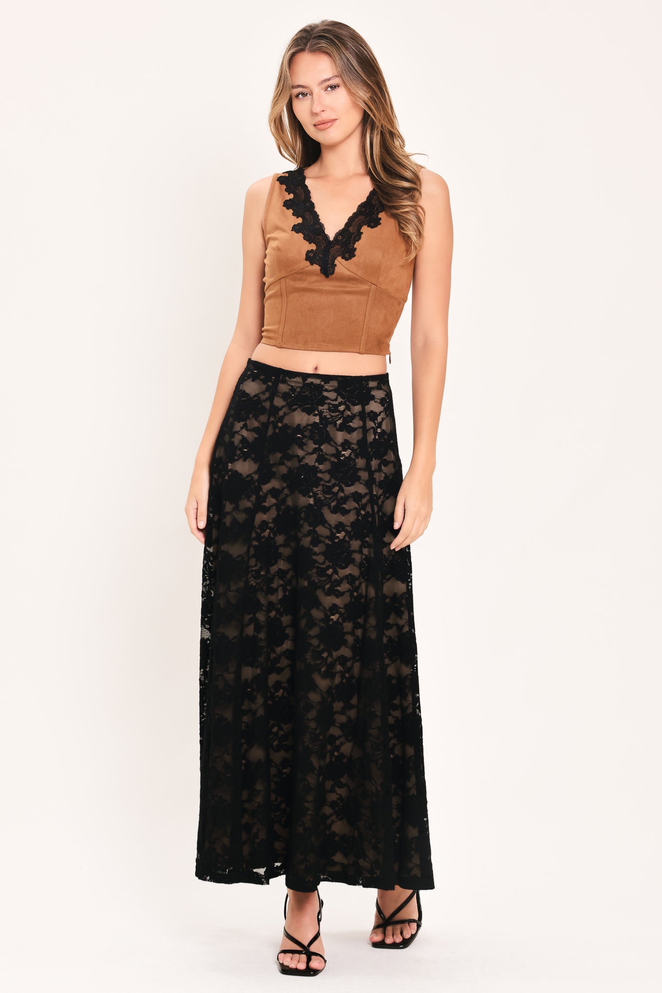 A woman modeling a two-piece outfit consisting of a brown velvet sleeveless crop top with black lace trim and a long black lace maxi skirt, against a plain white studio background.