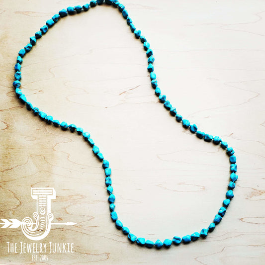 Turquoise beaded necklace on a light wooden surface with 'The Jewelry Junkie' logo.
