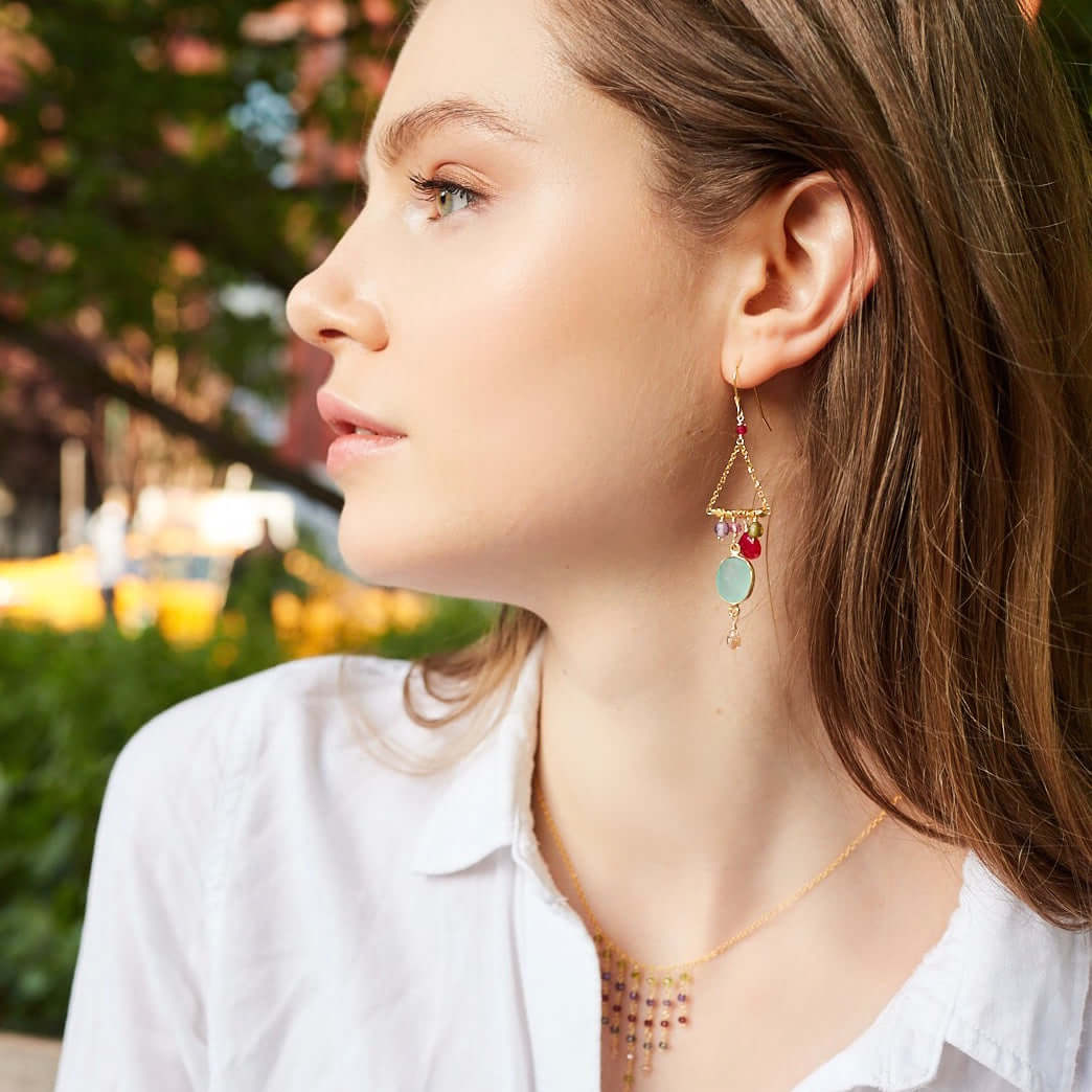 Close-up of a woman wearing colorful earrings with a blurred outdoor background