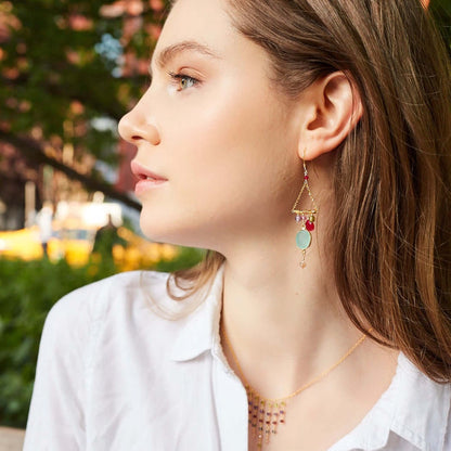 Close-up of a woman wearing colorful earrings with a blurred outdoor background