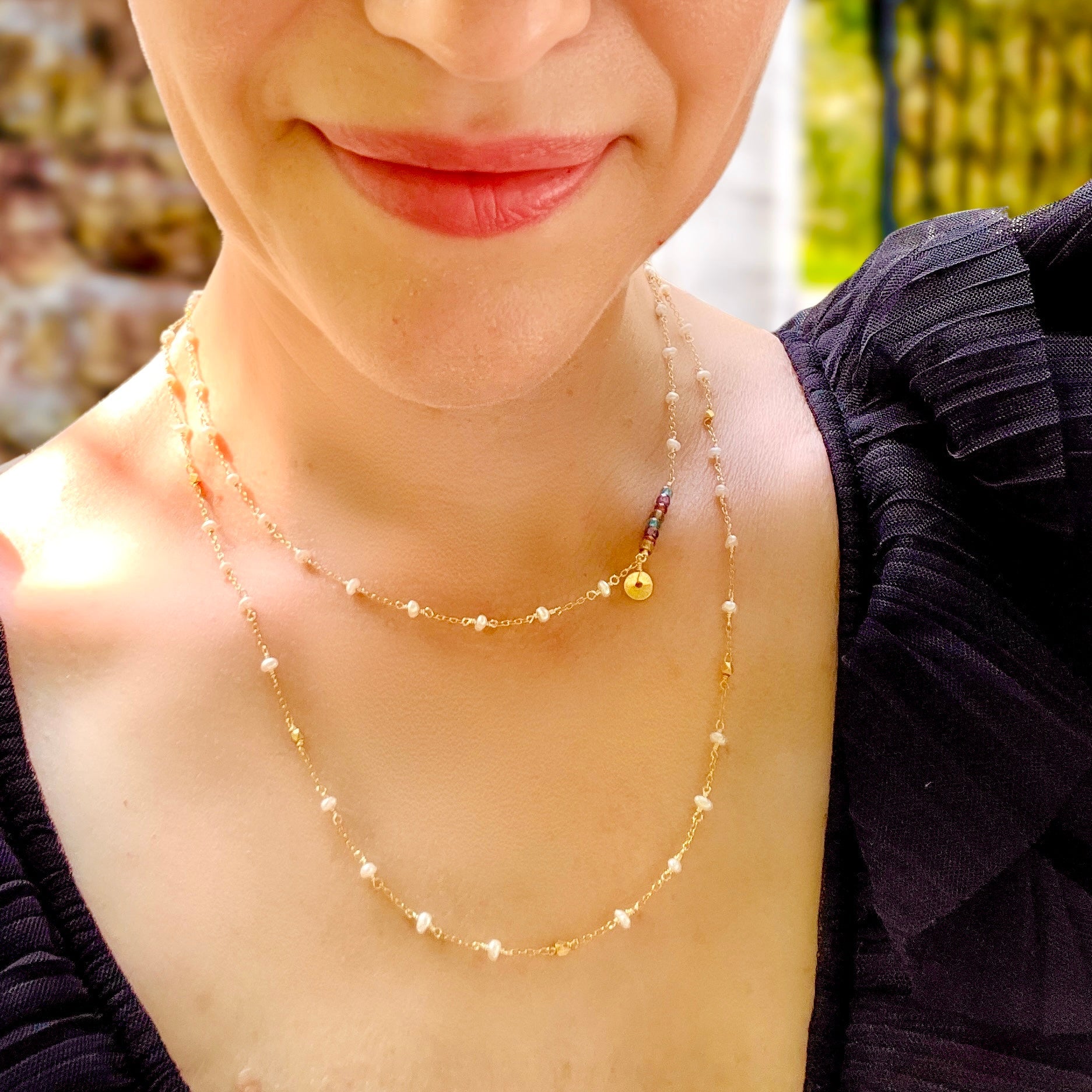 Close-up of a person wearing a gold necklace with small beads.