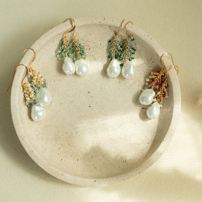 Set of pearl and gemstone earrings on a textured stone surface