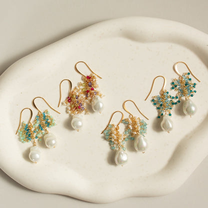 Set of gold earrings with pearls and gemstones on a white stone surface
