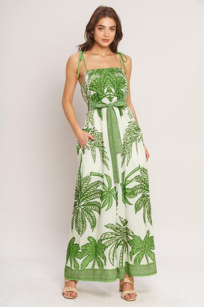 Woman wearing a green and white leaf-patterned dress on a plain background