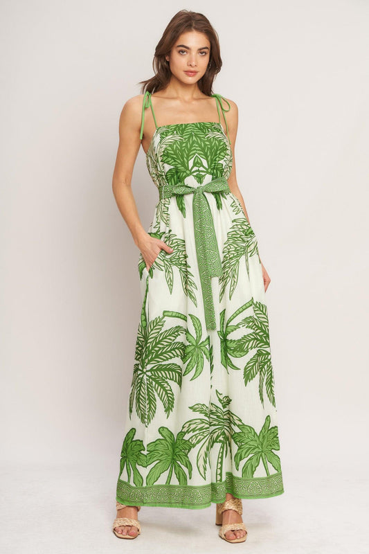 Woman wearing a green and white leaf-patterned dress on a plain background