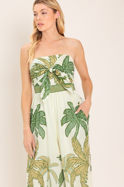Woman wearing a strapless dress with tropical leaf pattern on a plain background