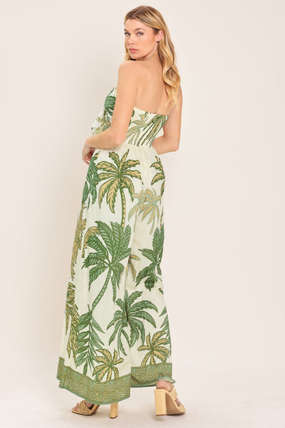Woman wearing a strapless dress with palm tree pattern on a plain background