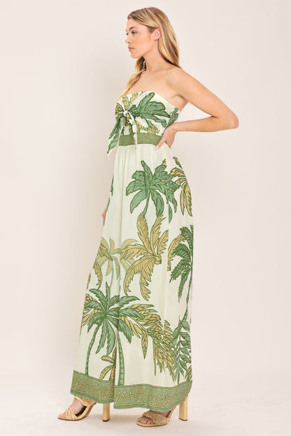 Woman wearing a strapless dress with palm tree pattern on a plain background