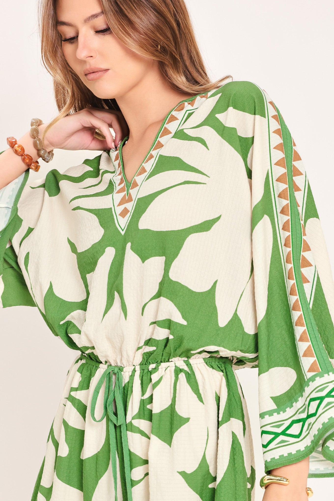Woman wearing a green and white patterned dress with a plain background