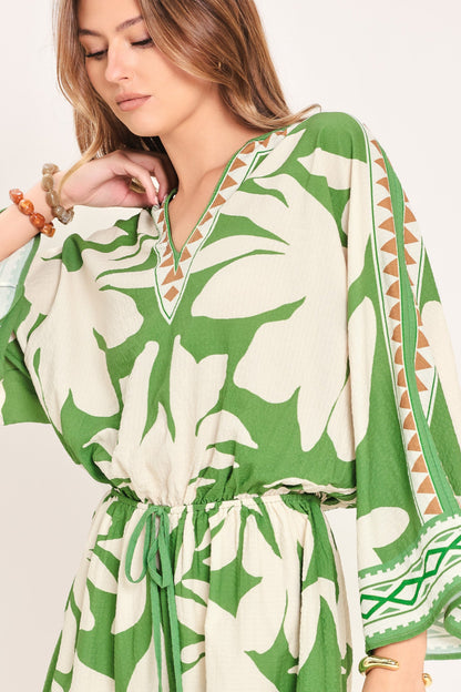 Woman wearing a green and white patterned dress with a plain background