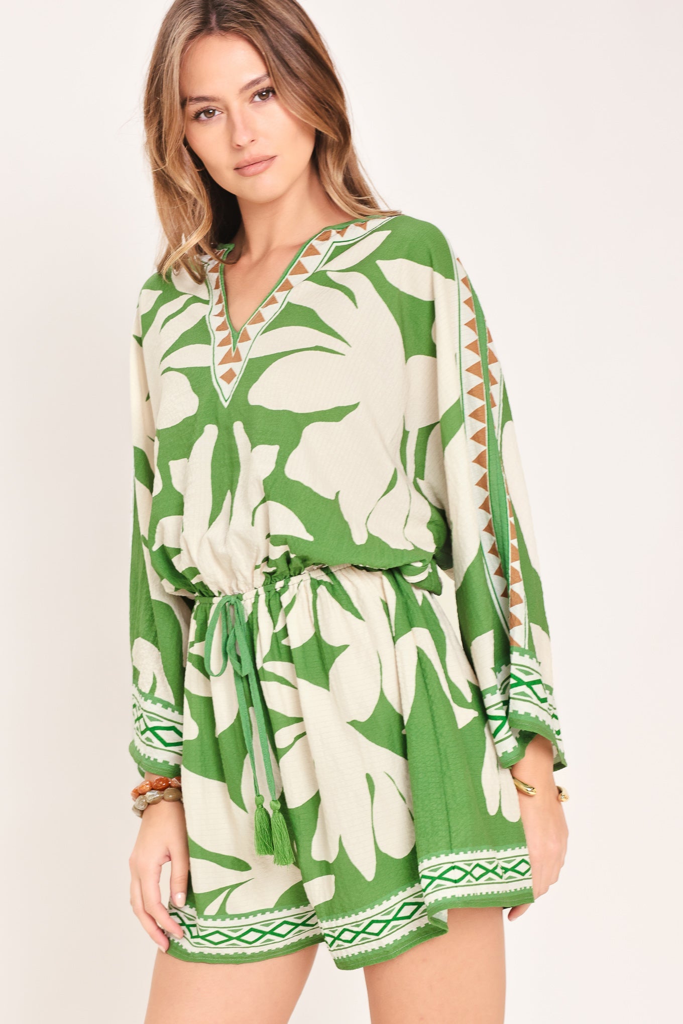 Woman wearing a green and white floral dress with a plain background