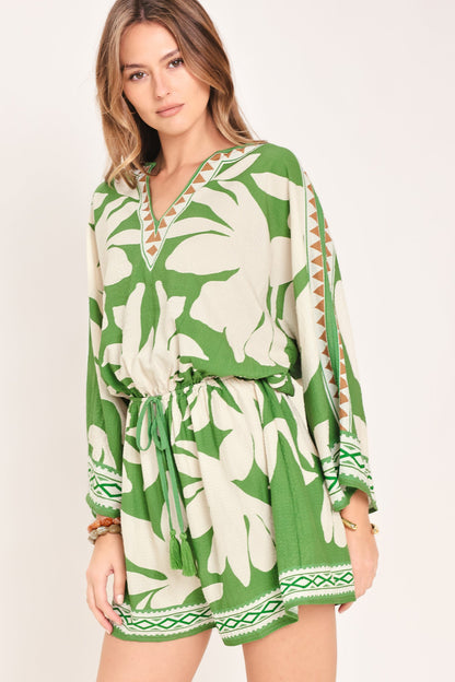 Woman wearing a green and white floral dress with a plain background
