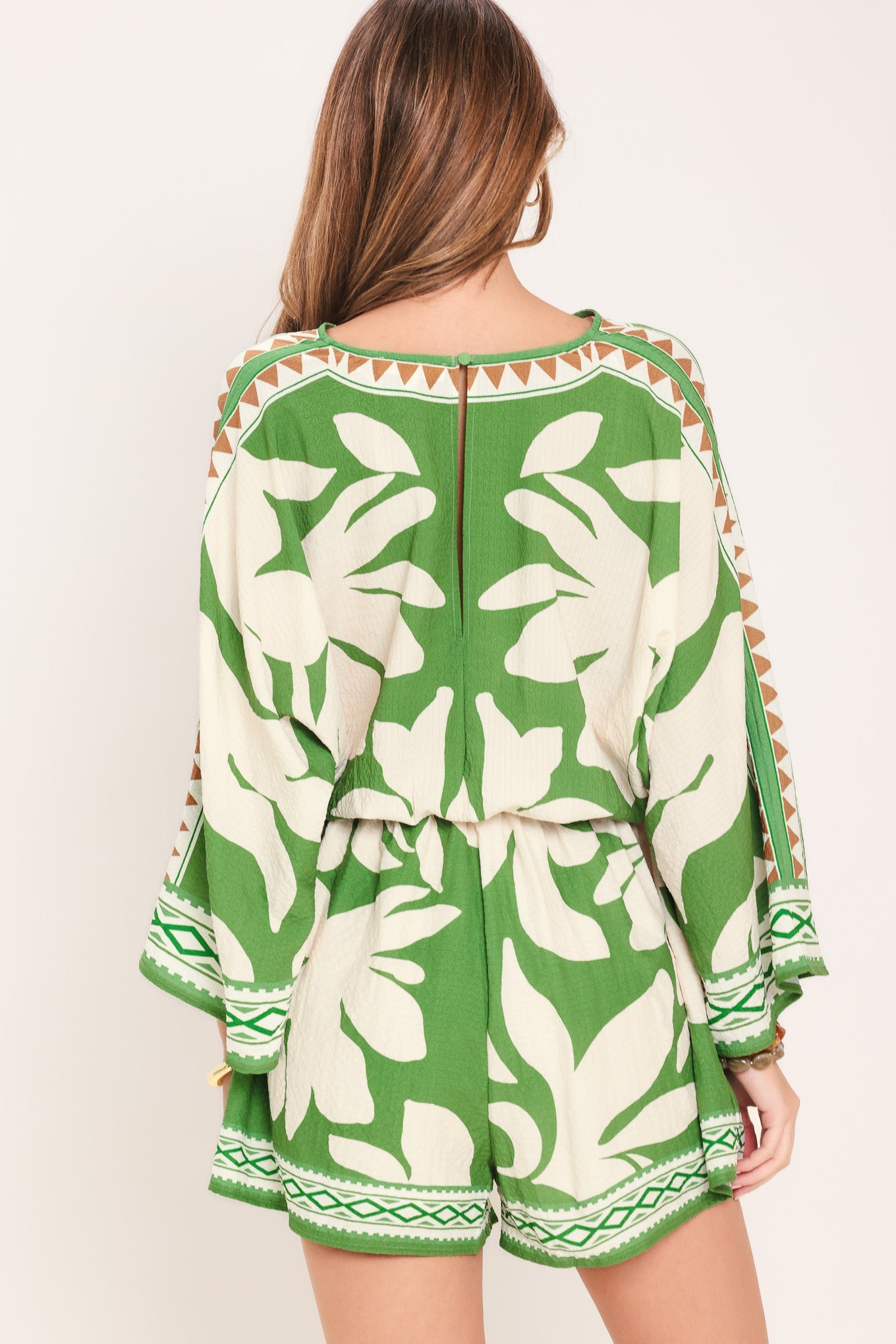 Green and white floral patterned romper on a plain background