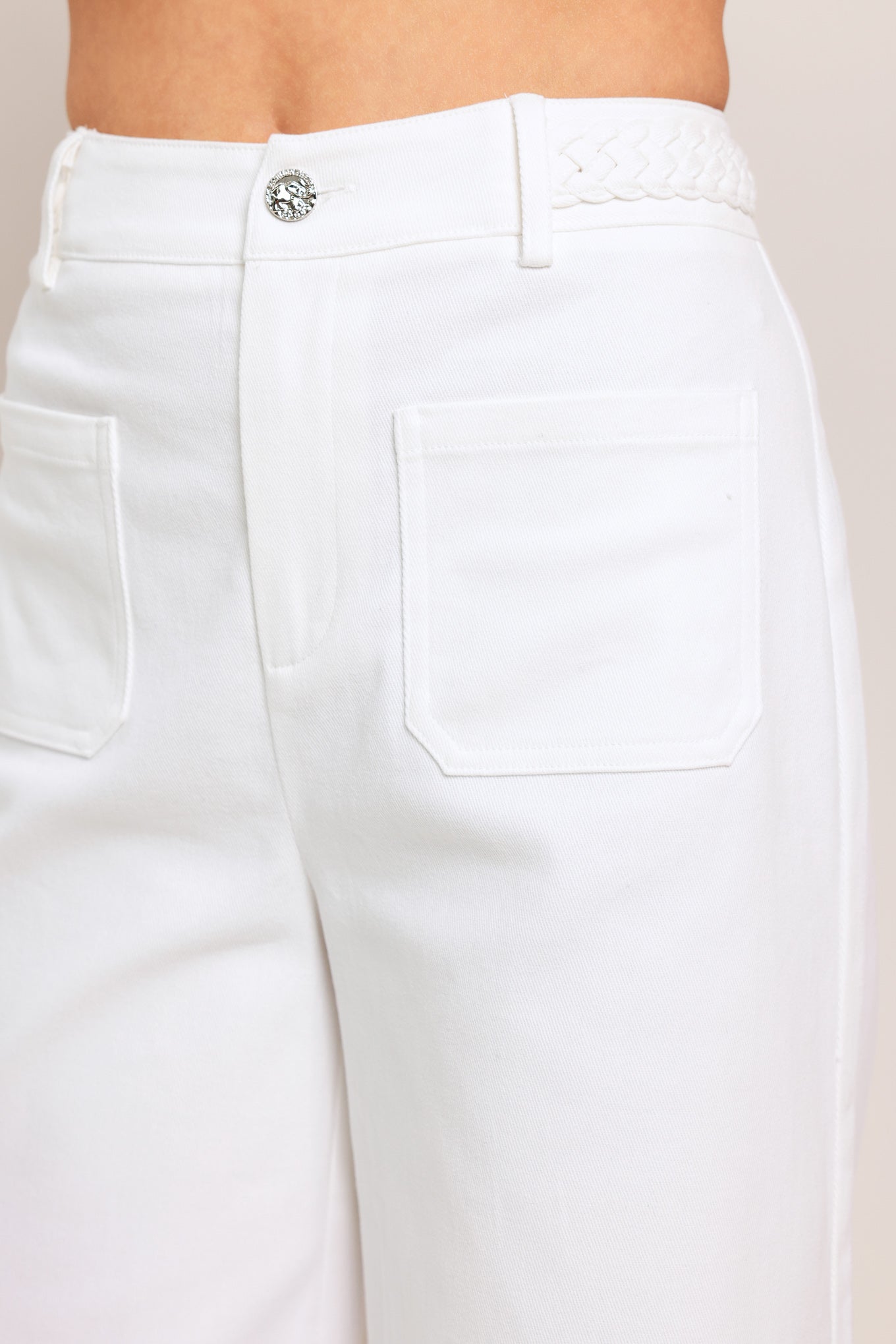 White pants with a close-up of the waistband on a beige background