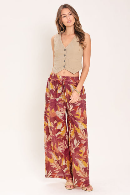 Woman wearing a beige vest and patterned pants on a white background