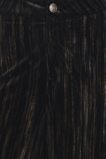 Close-up of a dark pleated fabric garment, likely a skirt or dress, featuring vertical pleats in black with subtle warm brown highlights and a small metallic button at the top.