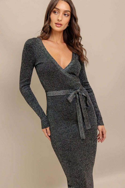 Woman wearing a dark gray knit wrap dress against a beige background