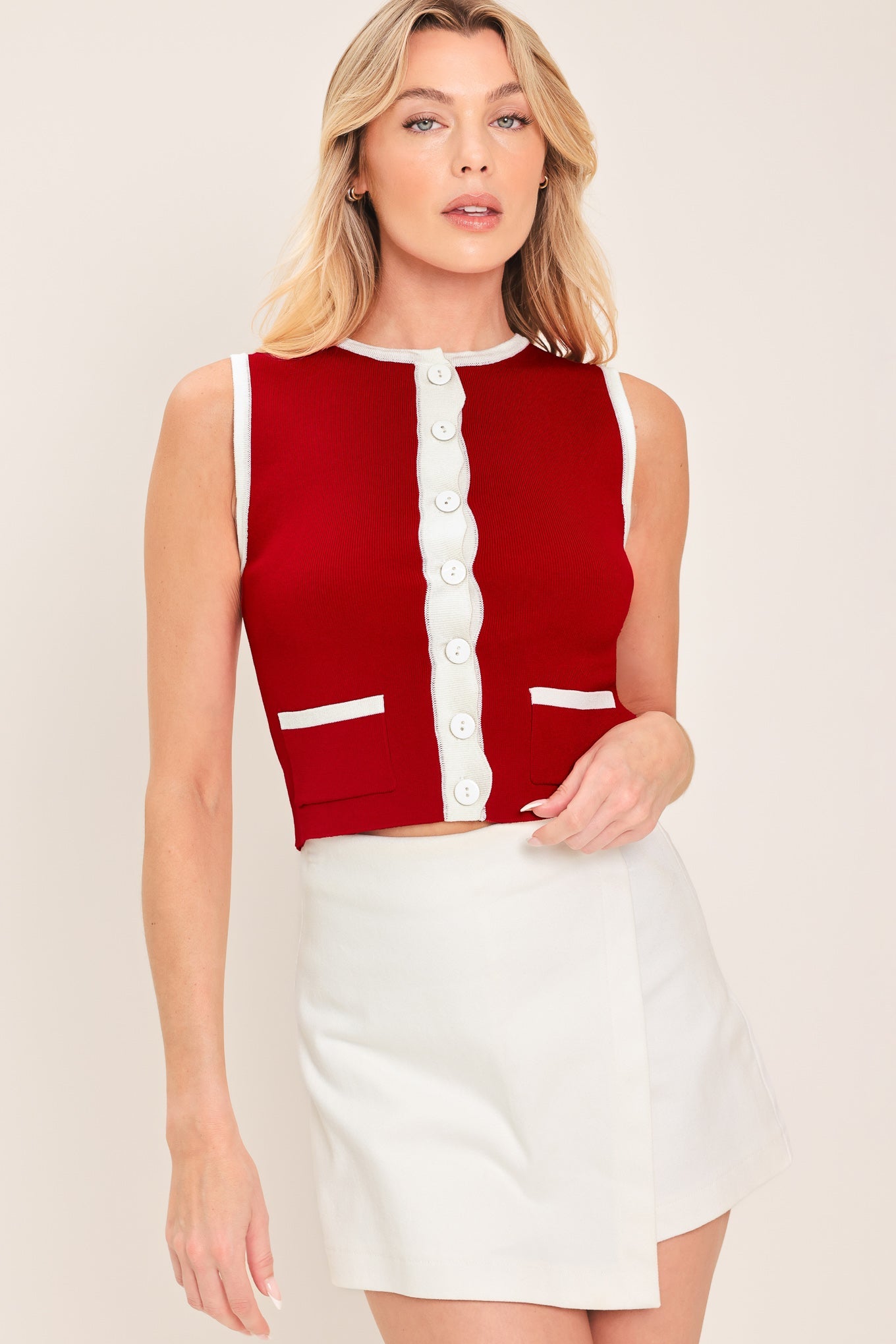 Woman wearing a red and white sleeveless top with a beige background