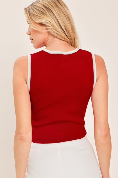 Woman wearing a red sleeveless top against a plain background