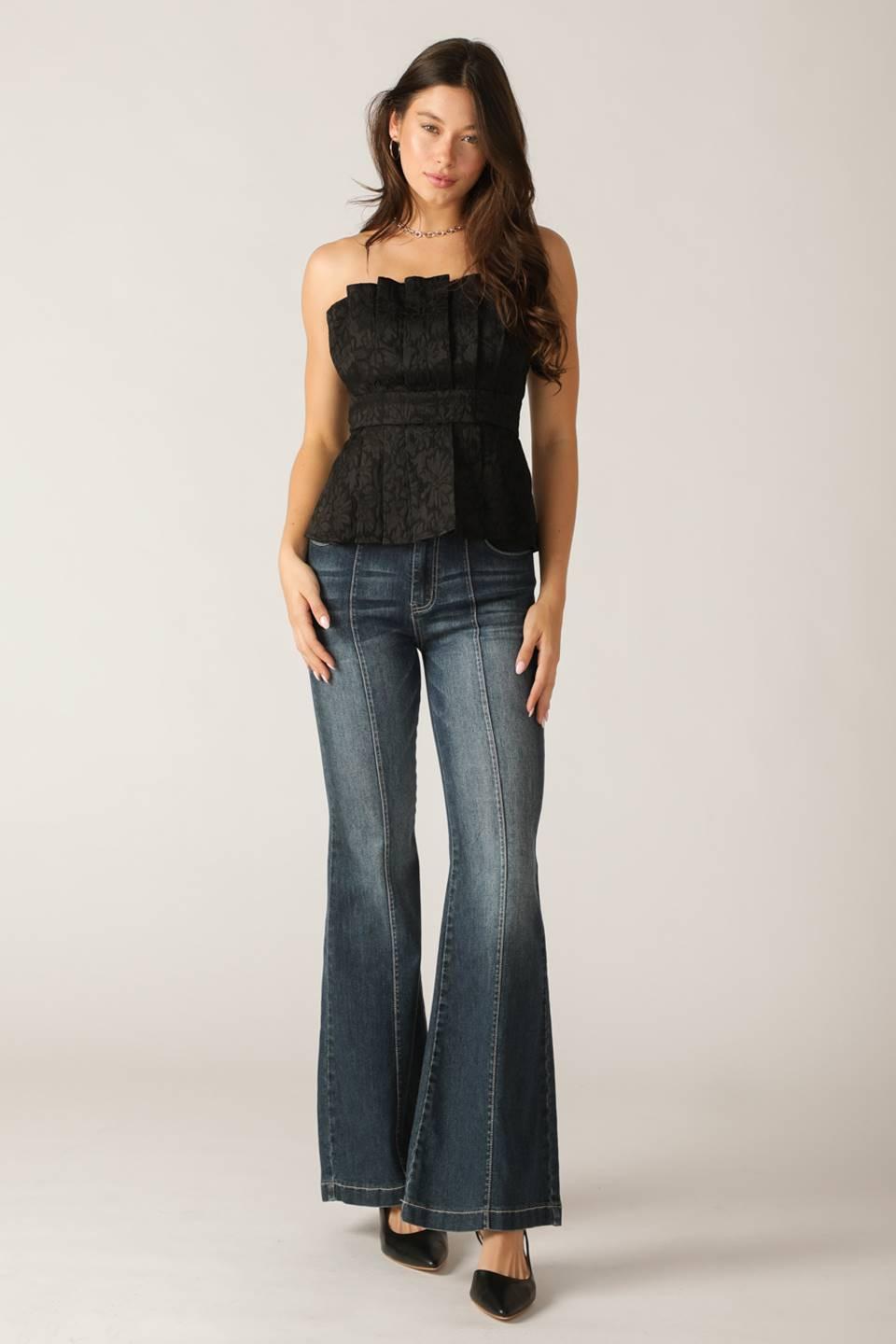 Woman wearing a black peplum top and blue jeans on a plain background