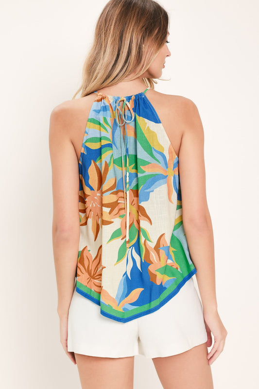 Woman wearing a colorful floral halter top and white shorts against a plain background