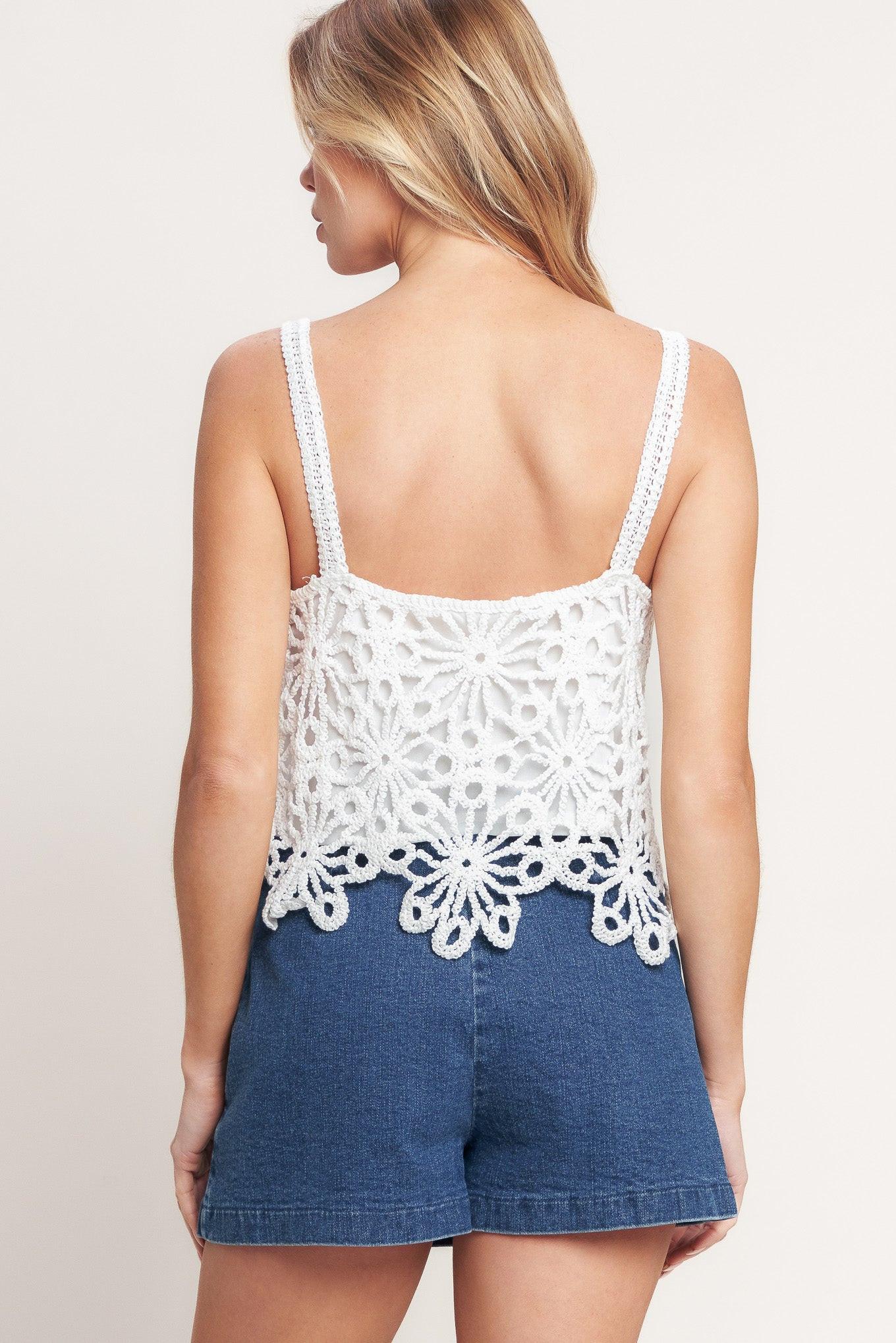 Woman wearing a white lace top and denim shorts on a plain background