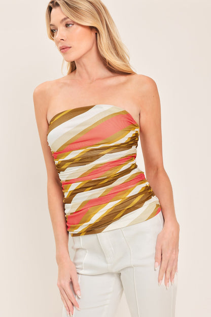 Woman wearing a strapless top with colorful geometric pattern on a plain background