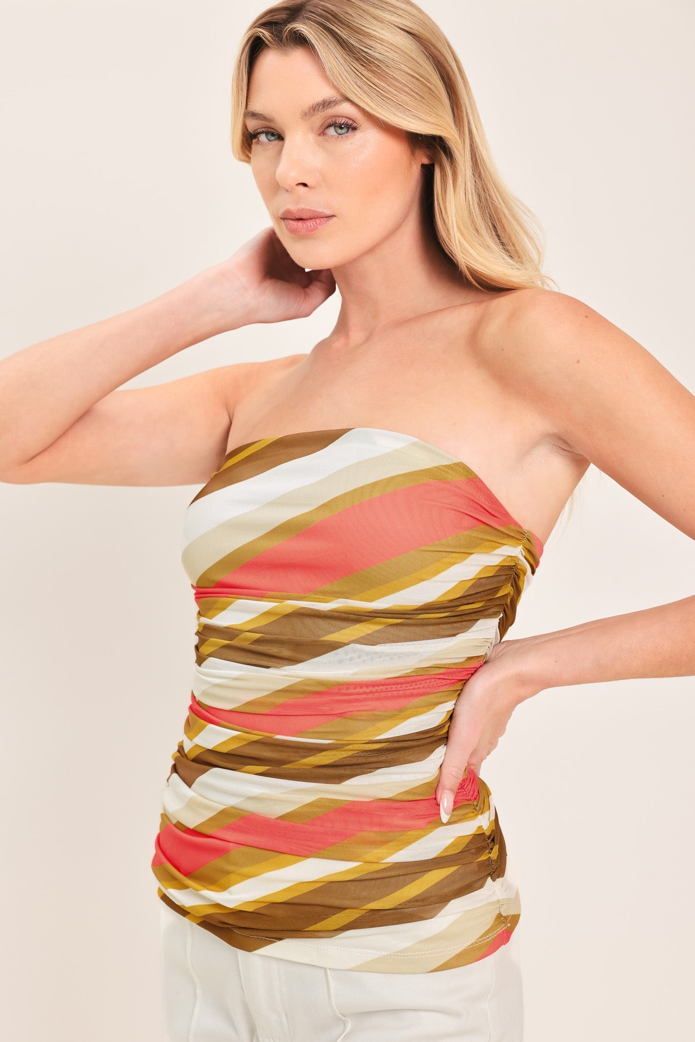 Woman wearing a strapless, multicolored striped top against a plain background