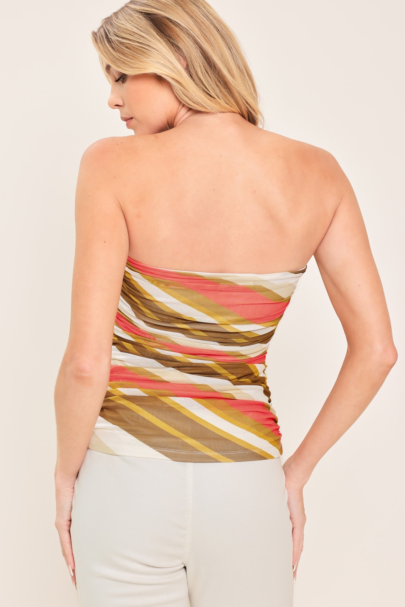 Woman wearing a strapless top with colorful stripes on a plain background