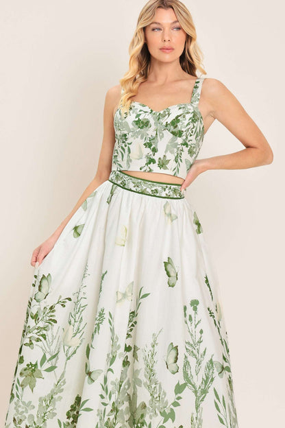 White fabric bustier top with a green floral and leaf print worn with a matching butterfly print skirt.