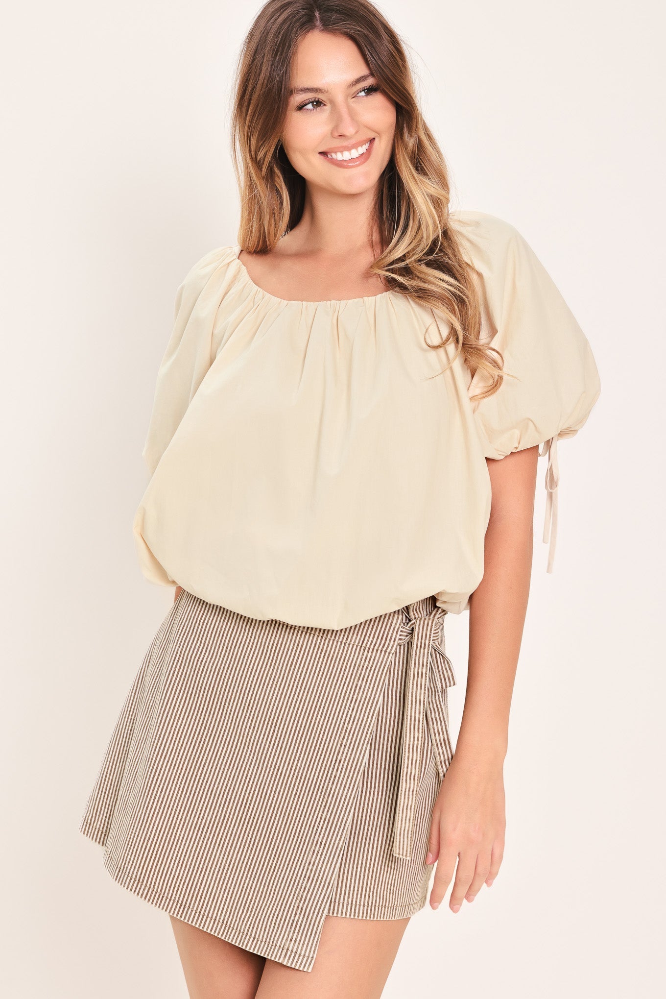Woman wearing a light yellow blouse and a checkered skirt on a plain background
