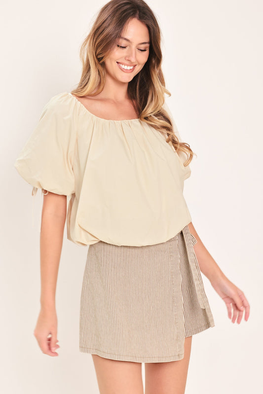 Woman wearing a light-colored blouse and plaid skirt on a plain background