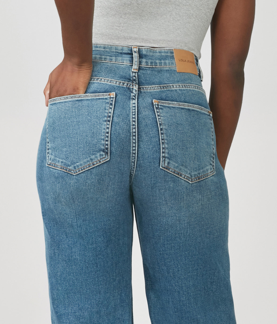 Blue jeans worn by a person on a plain background