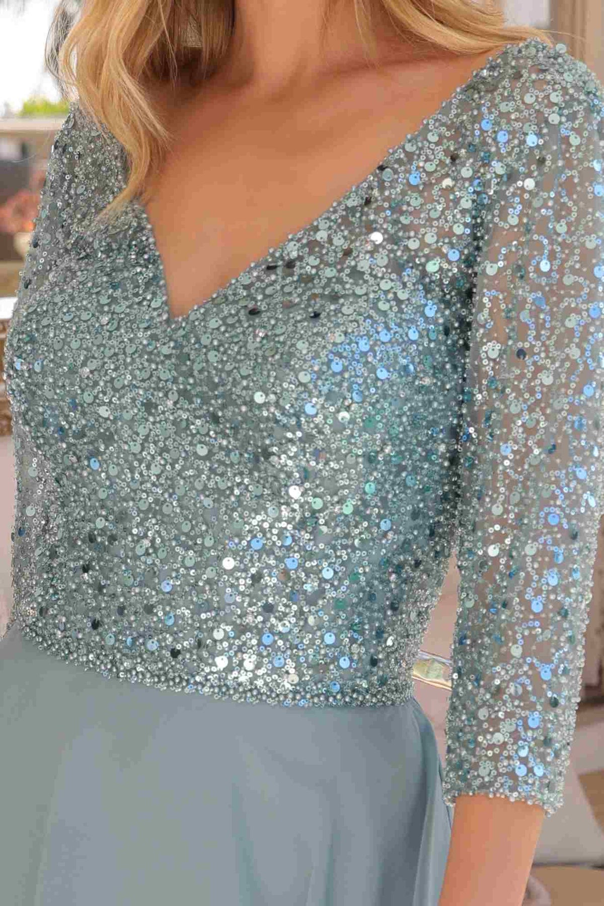 Close-up of a person wearing a sparkly silver top with long sleeves.