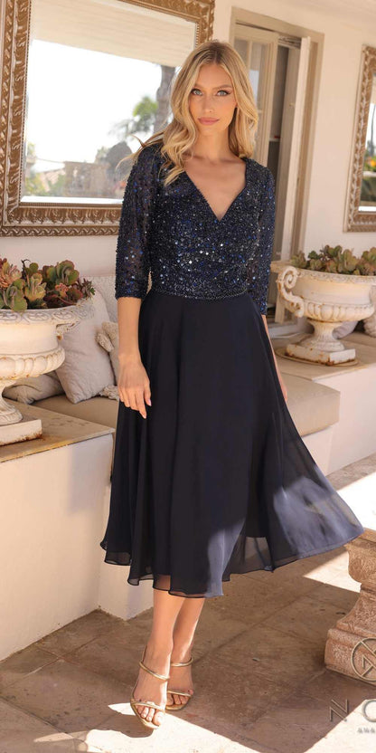 Woman wearing a navy blue dress with sequin top in an elegant indoor setting.
