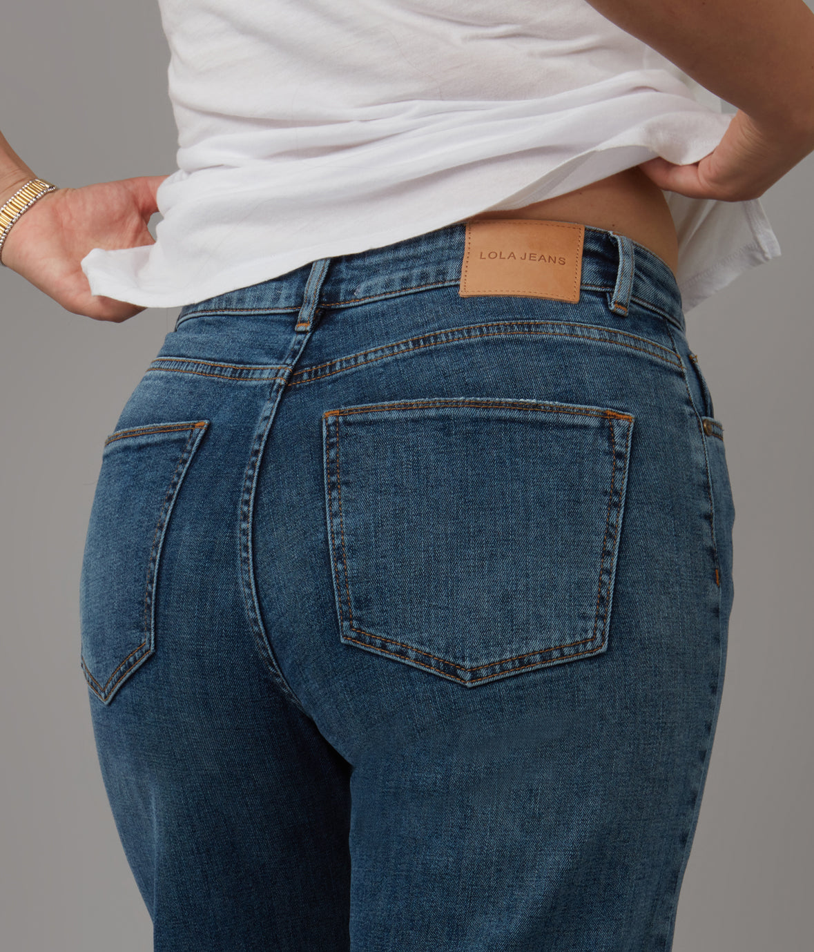 Person wearing blue jeans with a visible brand label on a gray background