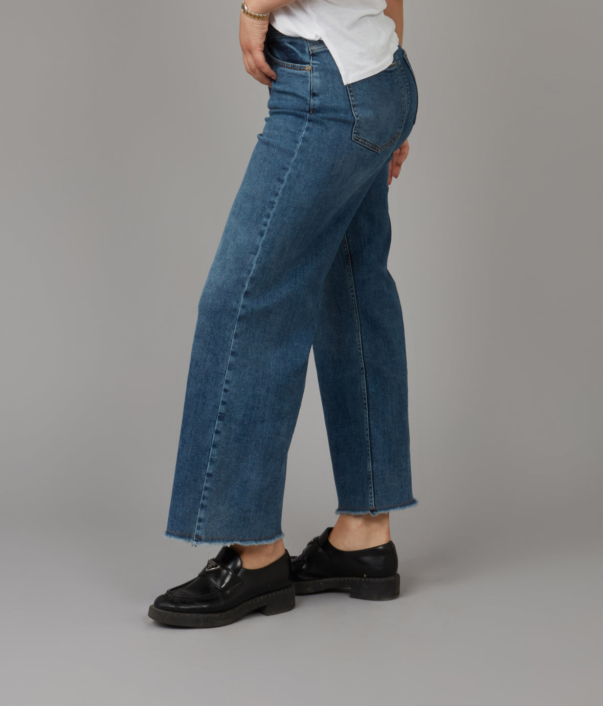 Person wearing blue jeans and black shoes on a gray background